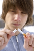 Young man breaking cigarette in half